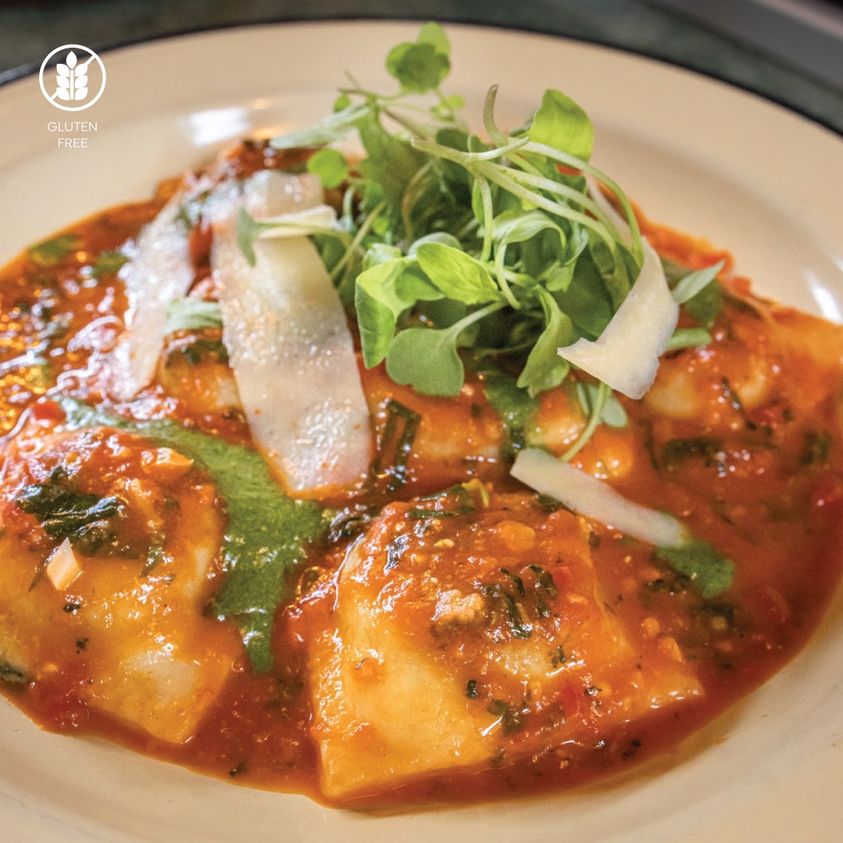Presentación del plato de raviolones de verdura con salsa de tomate y queso