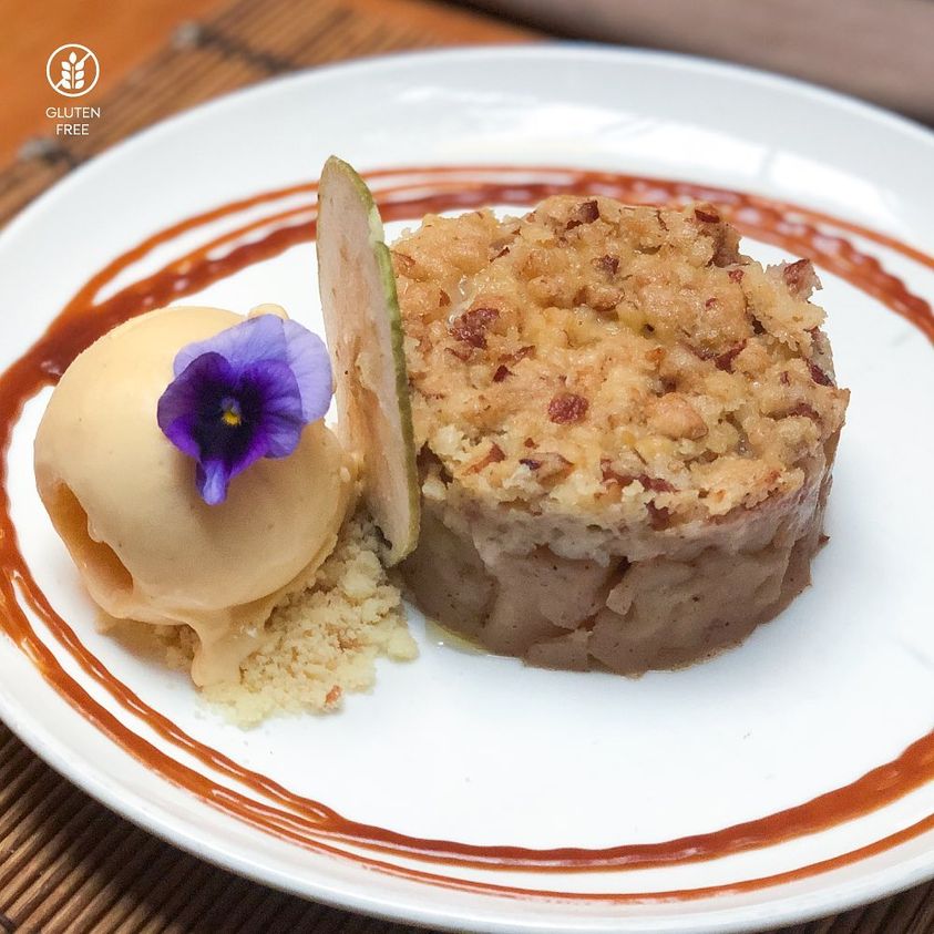plato de Crumble de manzana con helado de vainilla 
                     decorado con flor violeta